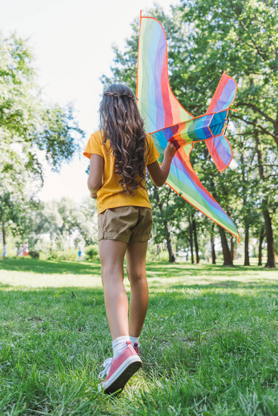 rear view of child playing with colorful kite in park  - Photo, image