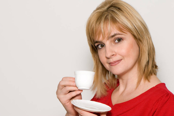 portrait of happy blonde woman holding white plate and coffee cup isolated on white background with copy space - 写真・画像