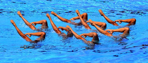 Synchronizované plavci vystupují z vody v akci. Synchronizovanému pohybu nohy. Synchronizované plavání tým provádějící synchronizované rutina komplikované pohyby ve vodě. - Fotografie, Obrázek