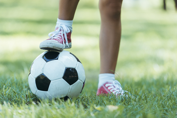 recortado tiro de niño de pie con pelota de fútbol en la hierba
 - Foto, Imagen