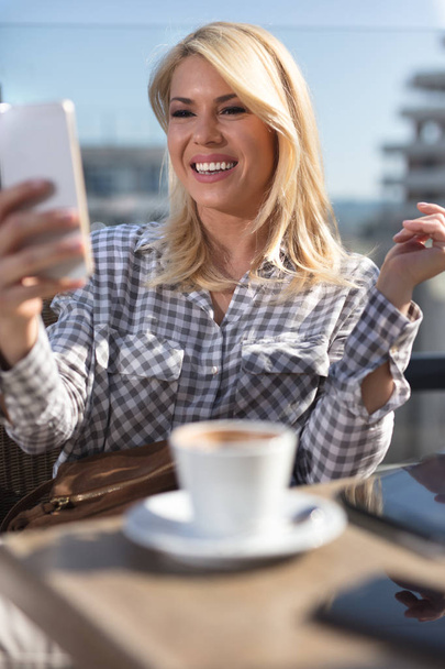 Woman typing write message on smart phone in a modern cafe - Фото, зображення