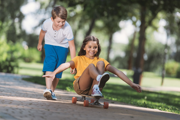 adorables niños felices divirtiéndose con longboard en parque
  - Foto, Imagen