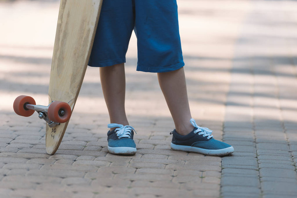 low section of child holding longboard in park - Valokuva, kuva