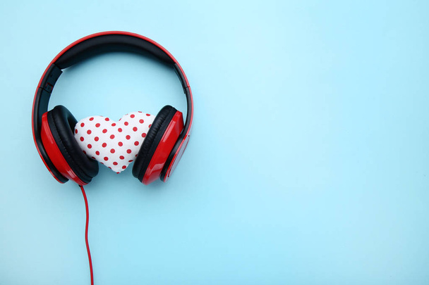Red headphones with fabric heart on blue background - 写真・画像