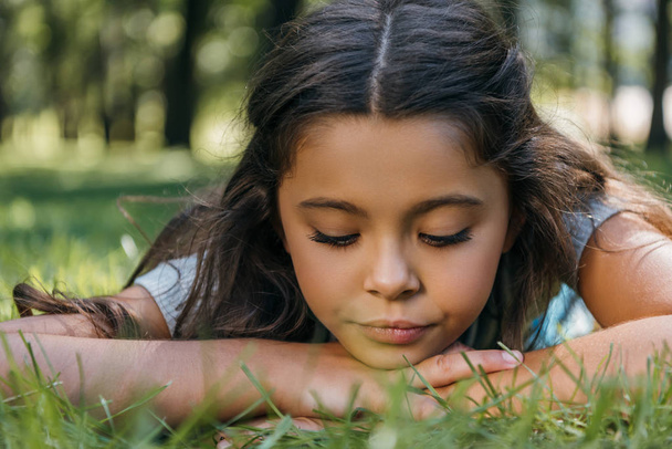 close-up view of adorable child lying on grass and looking down in park - Fotó, kép