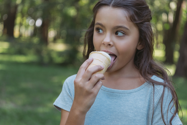 adorable child eating ice cream and looking away in park - Φωτογραφία, εικόνα
