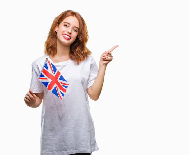 非常に幸せな側の手と指で指すの分離の背景の上イギリスの旗を保持している若い美しい女性 - 写真・画像