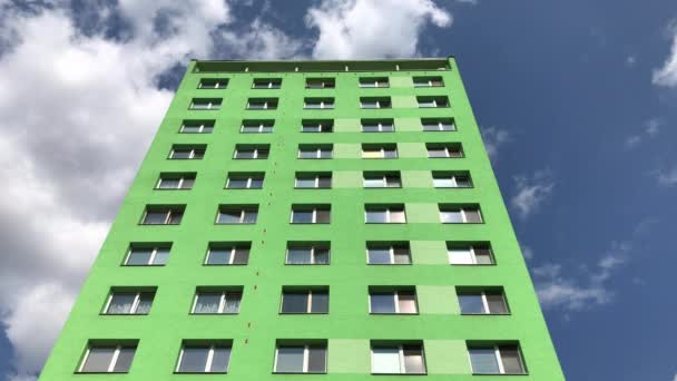 Foto estática de cara de bloque plano prefabricada verde con apartamentos en la calle en la ciudad bajo el cielo azul con la deriva de nubes blancas, reflejos del cielo en ventanas cerradas
 - Metraje, vídeo