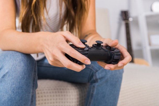обрезанный образ женщины, играющей в видеоигры с джойстиком дома
  - Фото, изображение