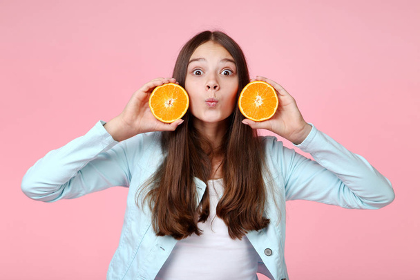 Young girl with orange fruit on pink background - 写真・画像