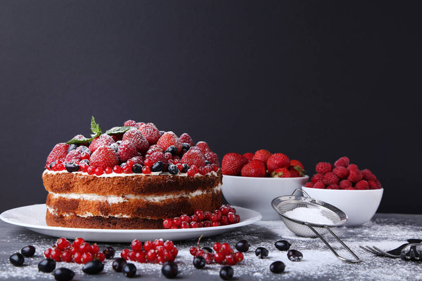 Homemade biscuit cake with berries and powdered sugar on grey wooden table - Foto, immagini