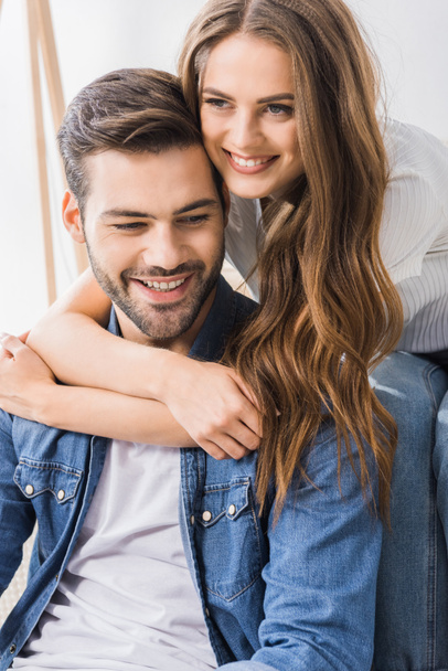 close up of beautiful smiling woman embracing boyfriend while sitting on floor at home  - Photo, Image