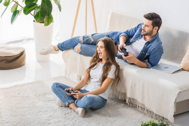excité jeune femme jouer jeu vidéo avec petit ami à la maison
  - Photo, image