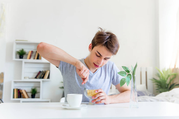 Young man drinking coffee and having breakfast - Photo, Image
