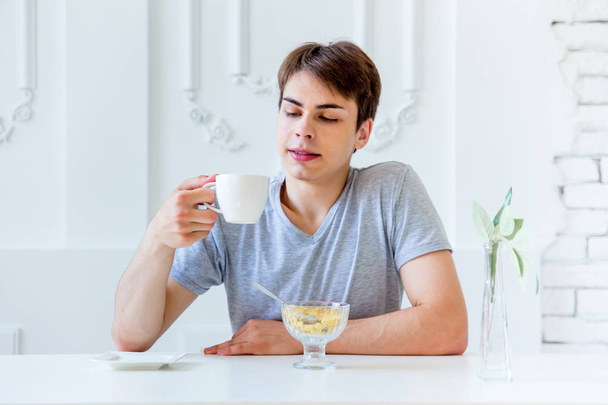Young man drinking coffee and having breakfast - Foto, Imagem