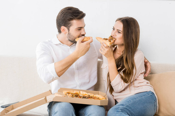 portrait of young couple eating pizza at home - Fotó, kép