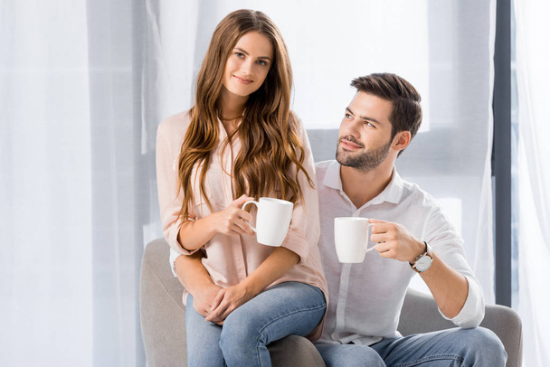 πορτρέτο των νέων αγάπη ζευγάρι με φλυτζάνια του καφέ στο σπίτι - Φωτογραφία, εικόνα