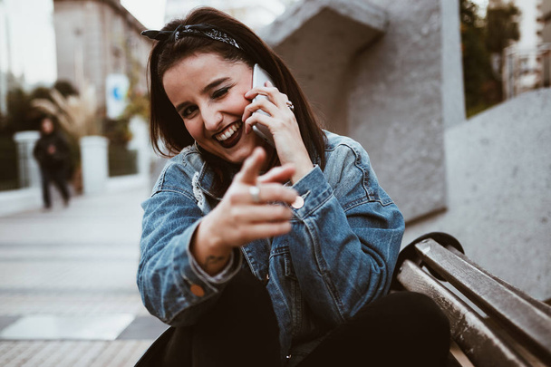 Δροσερό και όμορφο νεαρή γυναίκα μιλώντας στο τηλέφωνο στην πόλη. Urban στυλ - Φωτογραφία, εικόνα