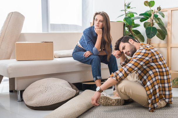 pensive young couple at new house with cardboard boxes, moving home concept - Foto, Imagem