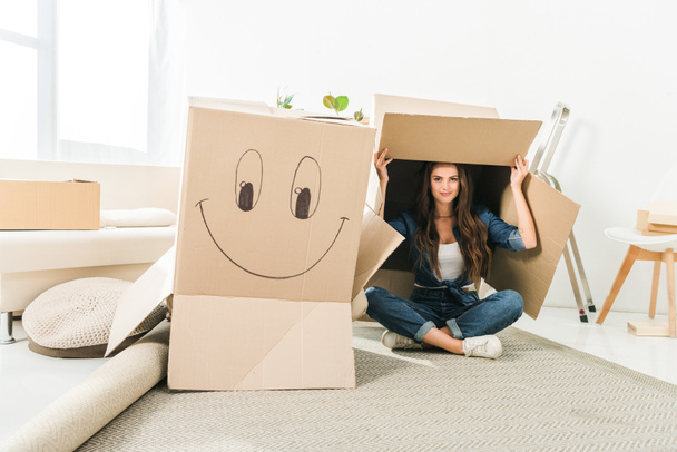 young woman with cardboard boxes sitting on floor at new home - Photo, Image