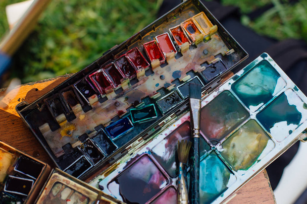 Palette of watercolor paints and brushes on the wooden background, close up. - Fotoğraf, Görsel