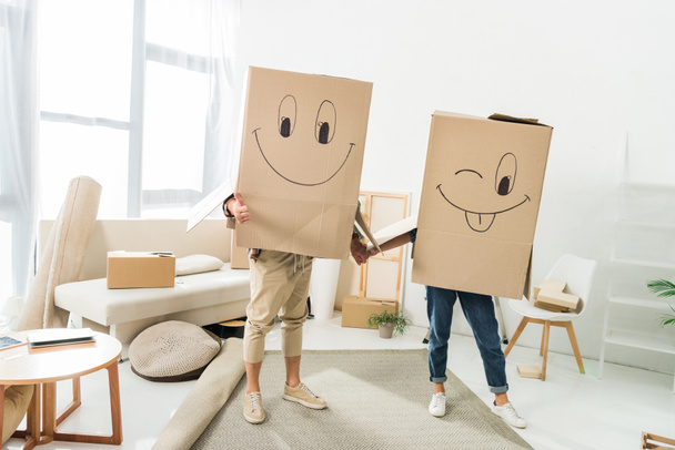 obscured view of couple with cardboard boxes on heads holding hands at new house, moving home concept - Фото, зображення