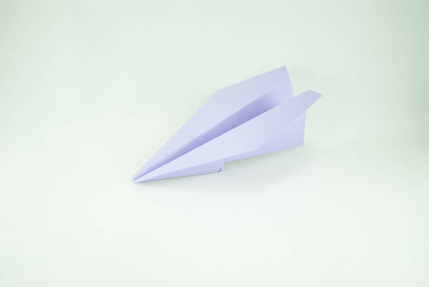 Ιώδες χάρτινο αεροπλανάκι σε λευκό φόντο, απομονωμένη. Έννοια (ιδέα) των αεροπορικών εταιρειών, της ελευθερίας, ηγεσία, επιτυχία και δημιουργικότητα. Γκρο πλαν - Φωτογραφία, εικόνα