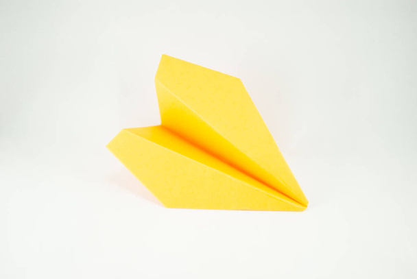 Avion en papier jaune sur fond blanc, isolé. Concept (idée) de compagnies aériennes, liberté, leadership, succès et créativité. Gros plan
 - Photo, image
