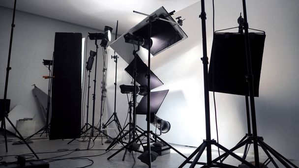 Configuración de iluminación en el estudio para obras comerciales como película fotográfica o producción de película de vídeo que utilizan mucha luz led de más de 1000 vatios con gran paraguas reflector de snoot softbox y trípodes
.  - Foto, imagen