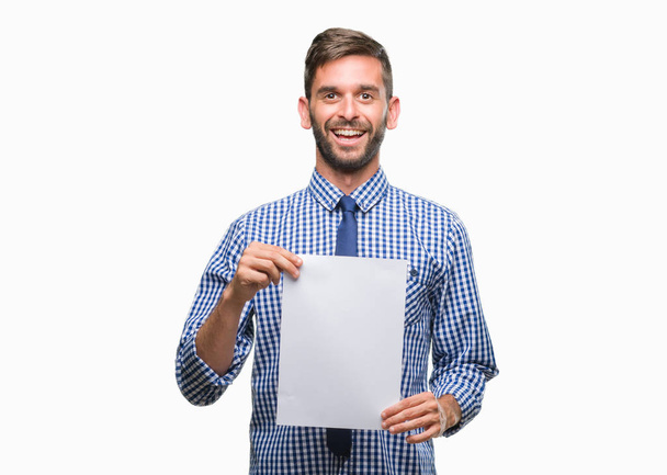 Young handsome man holding blank paper over isolated background with a happy face standing and smiling with a confident smile showing teeth - Foto, Bild