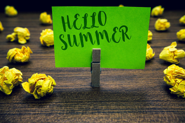 Conceptual hand writing showing Hello Summer. Business photo text Welcoming the warmest season of the year comes after spring Clothespin holding green paper note crumpled papers mistakes. - Photo, Image