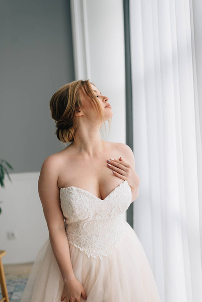 Wedding portrait of a bride with a big bust in a beautiful white fluffy dress - Foto, imagen