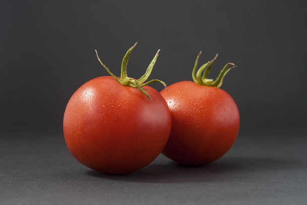Pomidory z łodygi, liści z czarnym tłem. Złym guście i brak cukru w nowoczesnym ogrodzie i odmian pomidora handlowe wynikały z hodowli pomidory dojrzewają równomiernie czerwony. - Zdjęcie, obraz