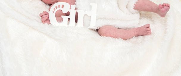 ноги новорожденного ребенка на белой пушистой вуали с надписью девушка
 - Фото, изображение