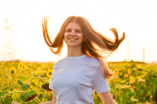 Portrait d'été de jeune femme heureuse en blanc avec les cheveux volants dans le champ de tournesol
 - Photo, image