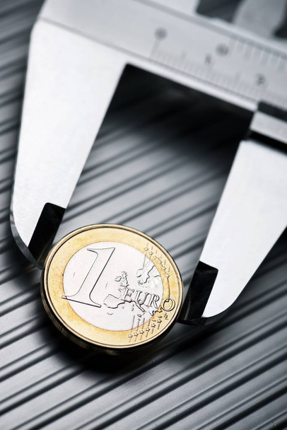 Манометр металла, измеряющий монету в один евро на металлической поверхности
. - Фото, изображение