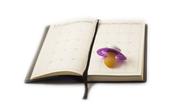 Zwangerschap concept. Fopspeen geplaatst op de kalender. - Foto, afbeelding