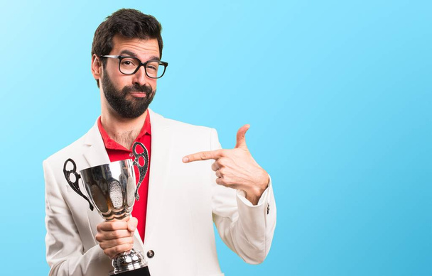 Brunetka muž s brýlemi držitelem trofeje na barevné pozadí - Fotografie, Obrázek