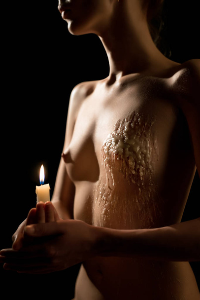 Nude woman with a candle in the dark - Foto, imagen