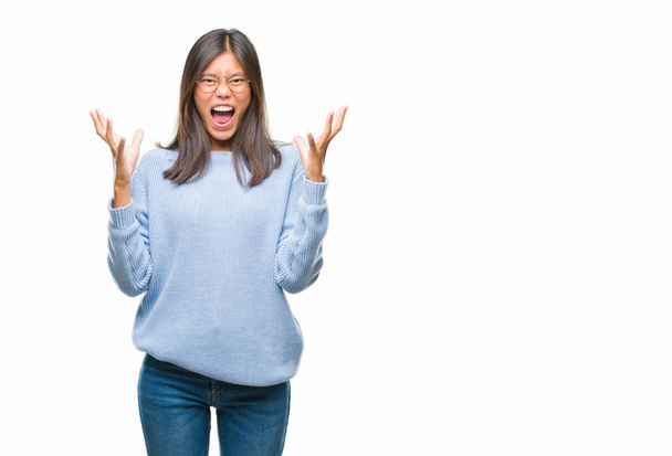Mujer asiática joven vistiendo suéter de invierno sobre fondo aislado celebrando loco y sorprendido por el éxito con los brazos levantados y los ojos abiertos gritando emocionados. Concepto ganador
 - Foto, imagen