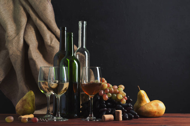 Вино в бутылках и стаканах на коричневой доске. Мешковина на тёмном фоне. Рядом с грушей и виноградником. Авторские ретуши. Место для текста
 - Фото, изображение