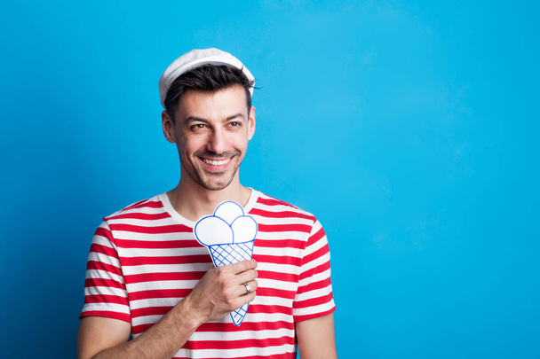 Portrait of a young man holding a paper ice cream in a studio. - Foto, Bild