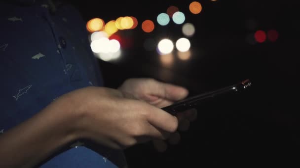 Kisfiú játszik a mobiltelefon, a város, este - Felvétel, videó