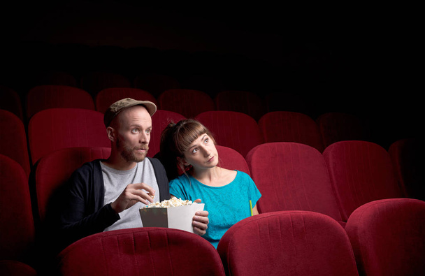 Young couple sitting at red movie theatre - Fotoğraf, Görsel