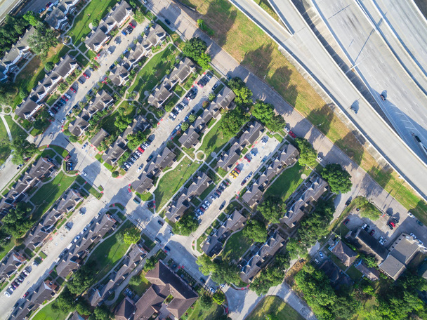 Üstgeçidin konut mahalle sınırlarının şehir Houston karayolu yakınındaki ev sahipliği yapmaktadır. Sıkıca paketlenmiş evleri, driveway erken sabah yeşil ağaçları havadan görünümü ile çevrili. Konut geliştirme - Fotoğraf, Görsel