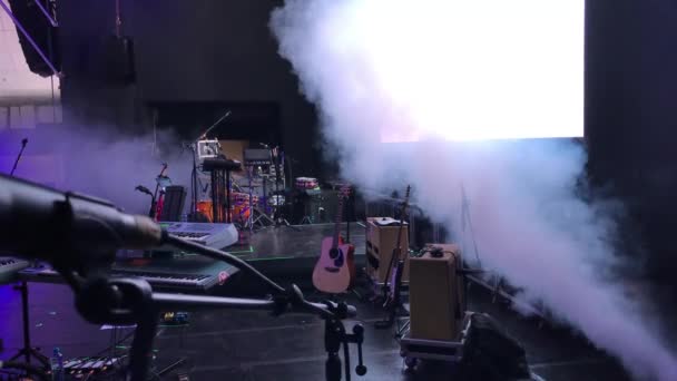 Grande tiro de um microfone em um palco com outros instrumentos e uma tela de monitor no fundo antes de um show
 - Filmagem, Vídeo