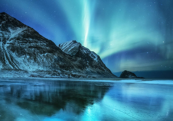 Nordlichter auf den Lofoten, Norwegen. grüne Nordlichter über den Bergen. Nachthimmel mit Polarlichtern. Nachtwinterlandschaft mit Polarlichtern und Spiegelungen auf der Wasseroberfläche. Natürlicher Hintergrund in Norwegen - Foto, Bild