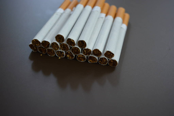 Νέα αποσυντίθενται πολλά τσιγάρα σε ένα καφέ ματ φόντο. - Φωτογραφία, εικόνα
