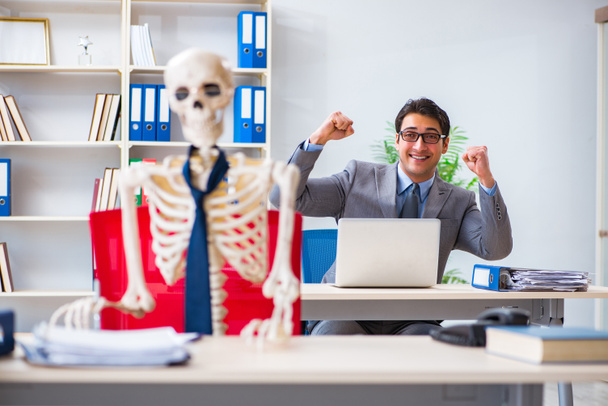 Empresário trabalhando com esqueleto no escritório - Foto, Imagem