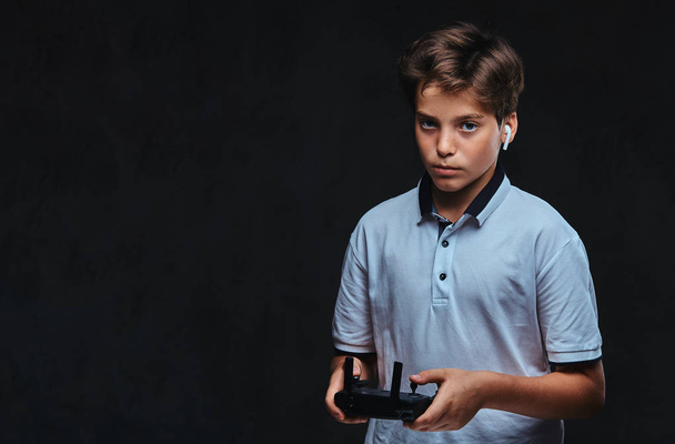 Portret młodego chłopca, ubranych w białe nosi t-shirt bezprzewodowy zestaw słuchawkowy posiada zdalnego sterowania. Na białym tle na ciemnym tle. - Zdjęcie, obraz